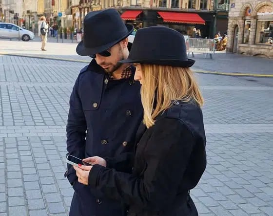 Deux joueurs déguisés en agents secrets consultent l’application dans la rue